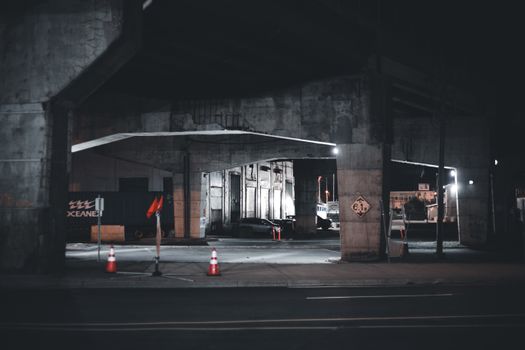 Dramatic nighttime urban underpass with moody lighting and empty streets.