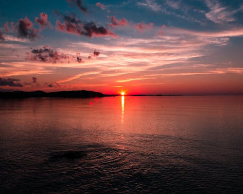 Body of Water Near Mountain during Sunset