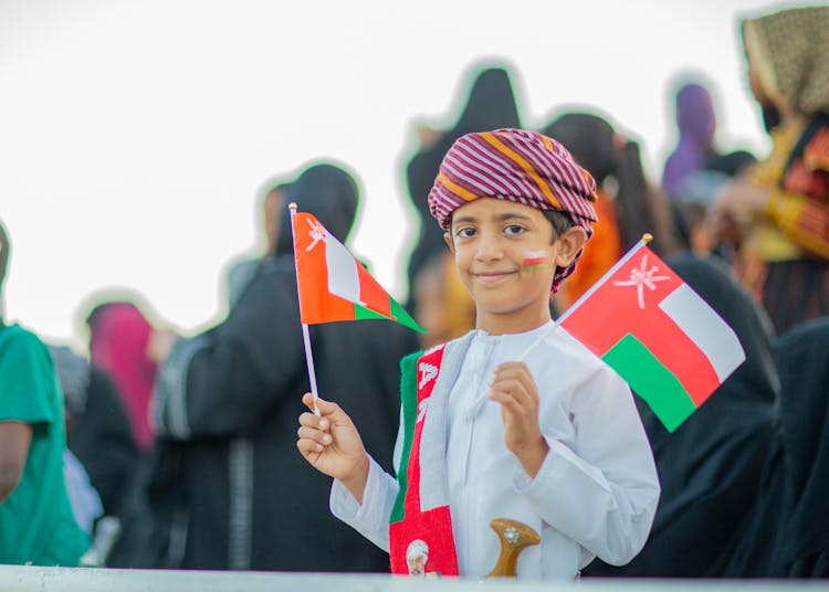 Young Arab Boy Holding Flags Of Oman 