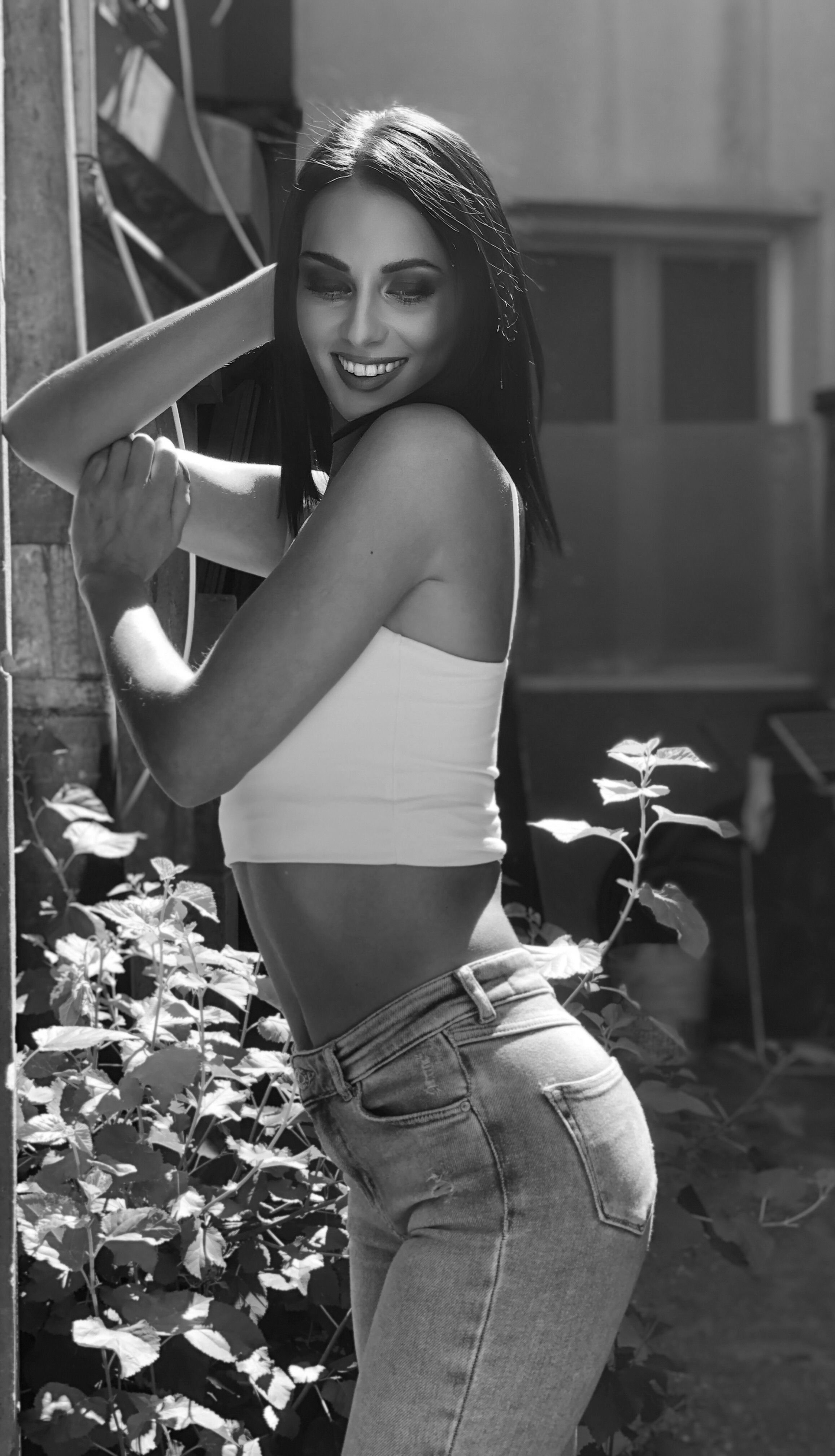 Elegant black and white portrait of a woman posing confidently outdoors, exuding style and charm.