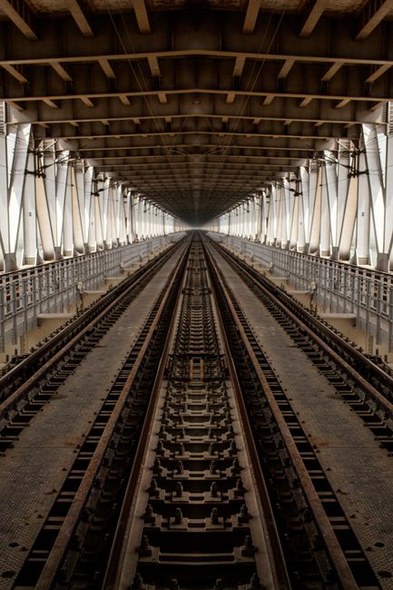 Fotomural Explora los intrincados patrones de acero de un puente ferroviario vacío en Patna, mostrando simetría geométrica y perspectiva.