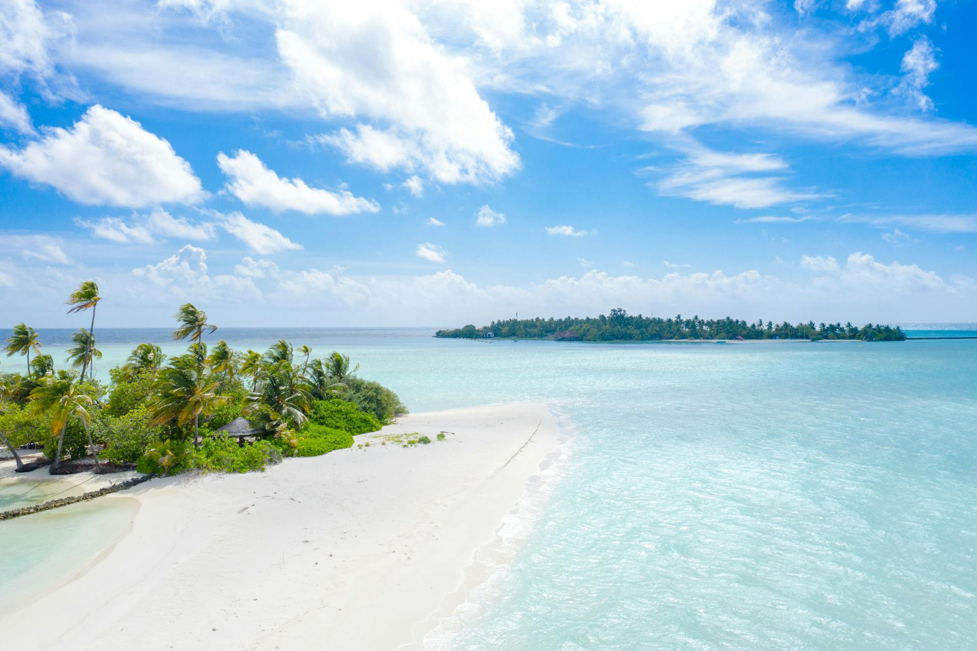 Aerial view of a beautiful tropical beach and island in the Maldives with clear blue water.