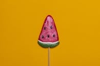 明亮的西瓜糖棒棒糖与充满活力的黄色背景相搭配，非常适合夏季主题