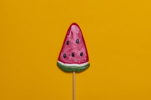 明亮的西瓜糖棒棒糖与充满活力的黄色背景相搭配，非常适合夏季主题