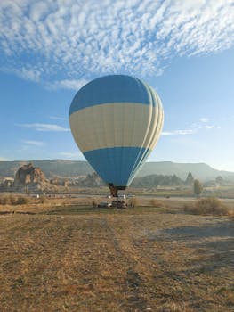 Scenic hot air balloon flying over Cappadocia's unique rock formations during sunrise.