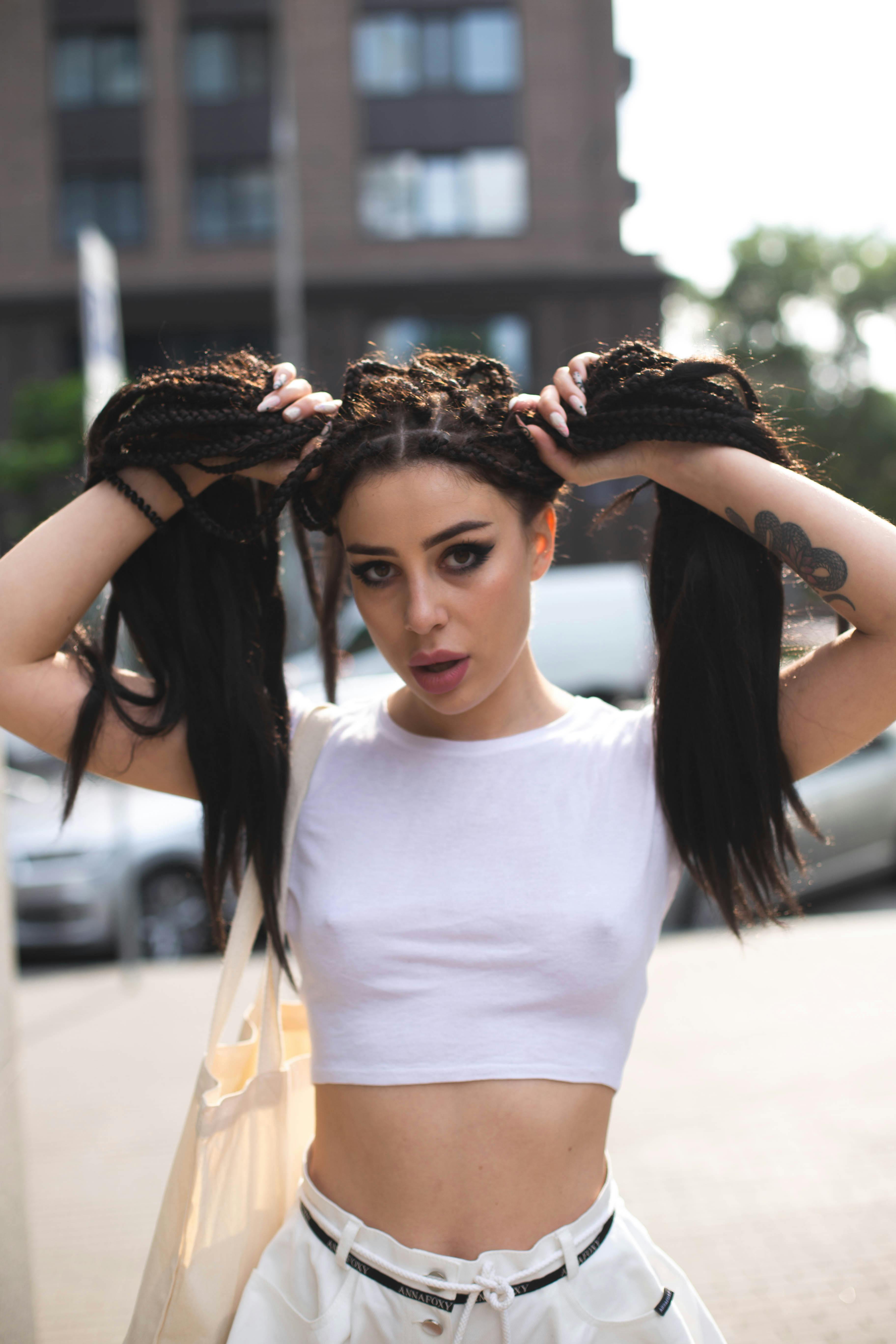 Fashionable woman posing outdoors, showcasing a stylish hairstyle with dreadlocks and a confident expression.