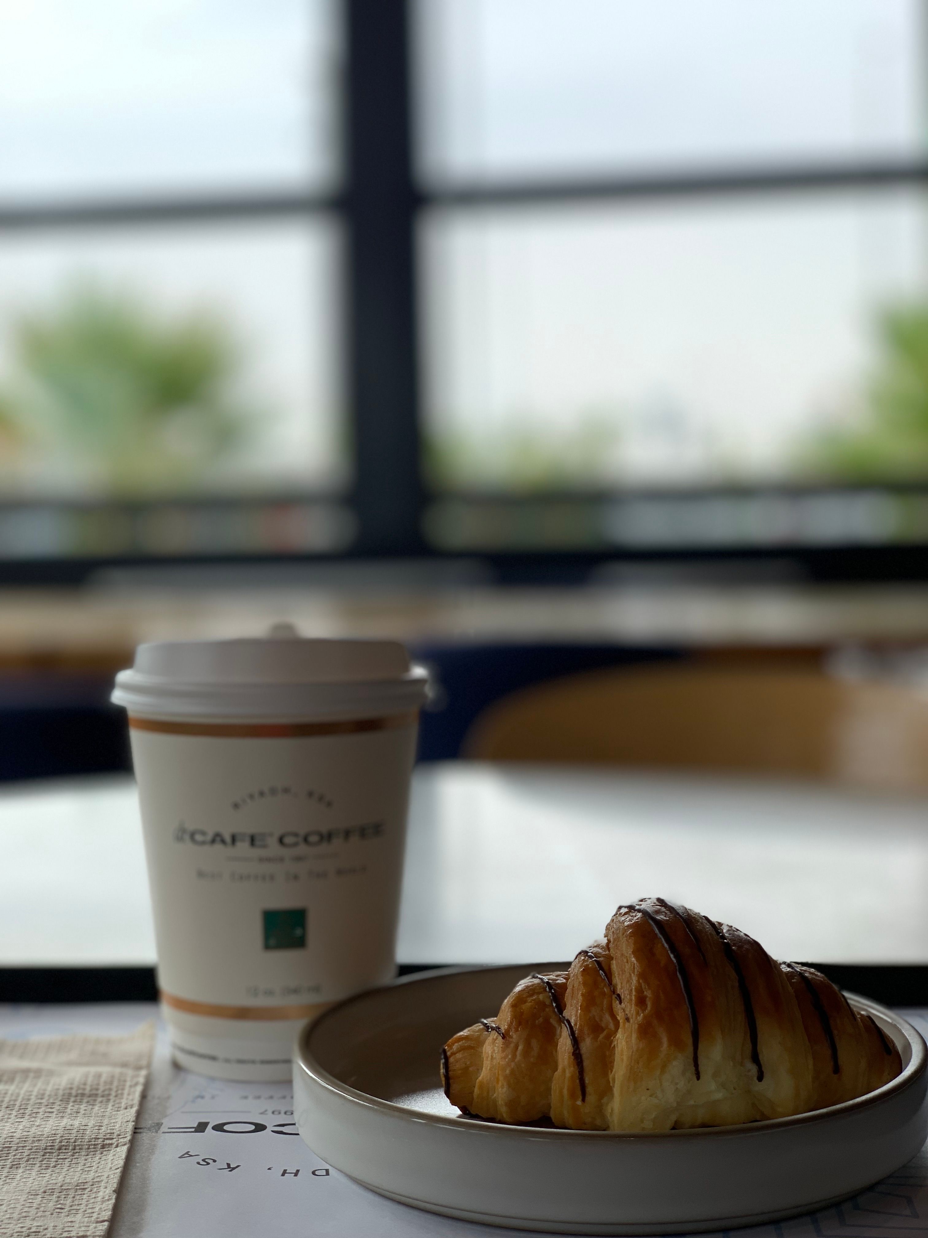 A chocolate croissant beside a cup of coffee