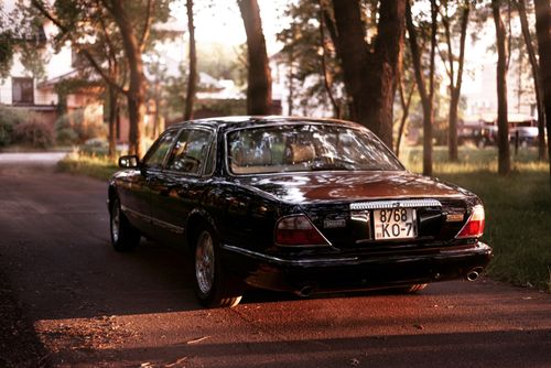 Free Elegant Jaguar sedan parked in scenic outdoor setting, reflecting warm evening light. Stock Photo