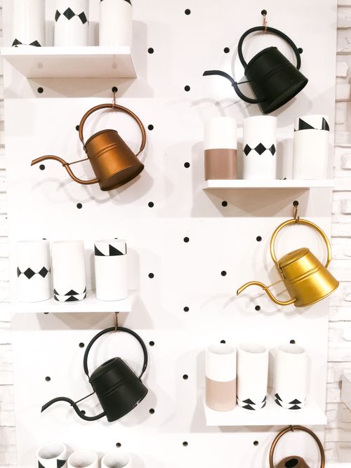Free Stylish home decor display featuring colorful watering cans and chic vases on shelves. Stock Photo
