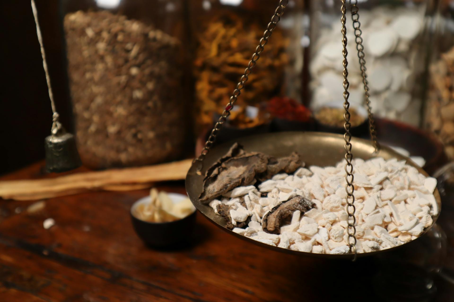 Close-up of traditional herbal medicine being weighed on a balance scale among various herbs.