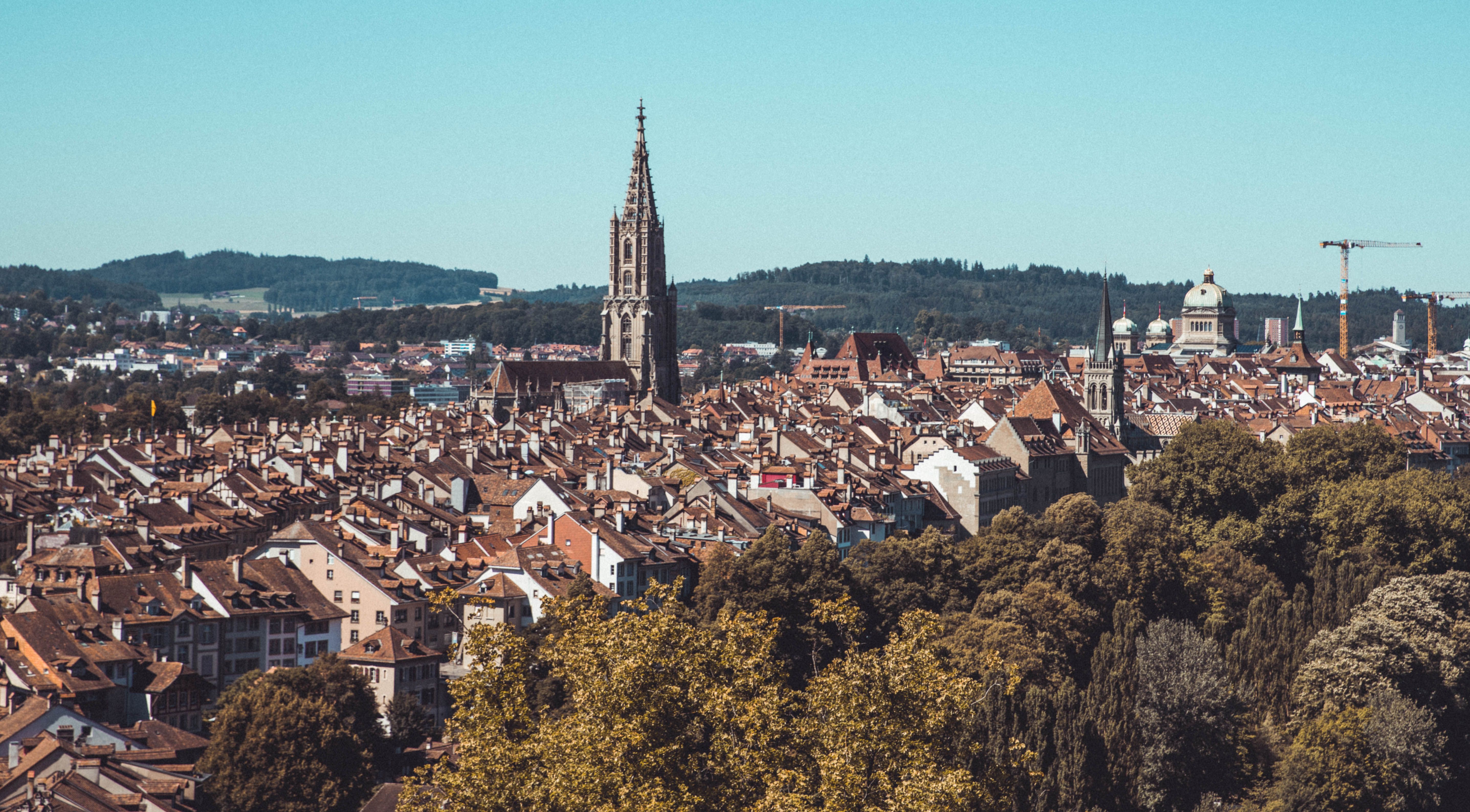 Aerial view of Bern, Switzerland featuring the iconic cathedral tower amidst historic rooftops.