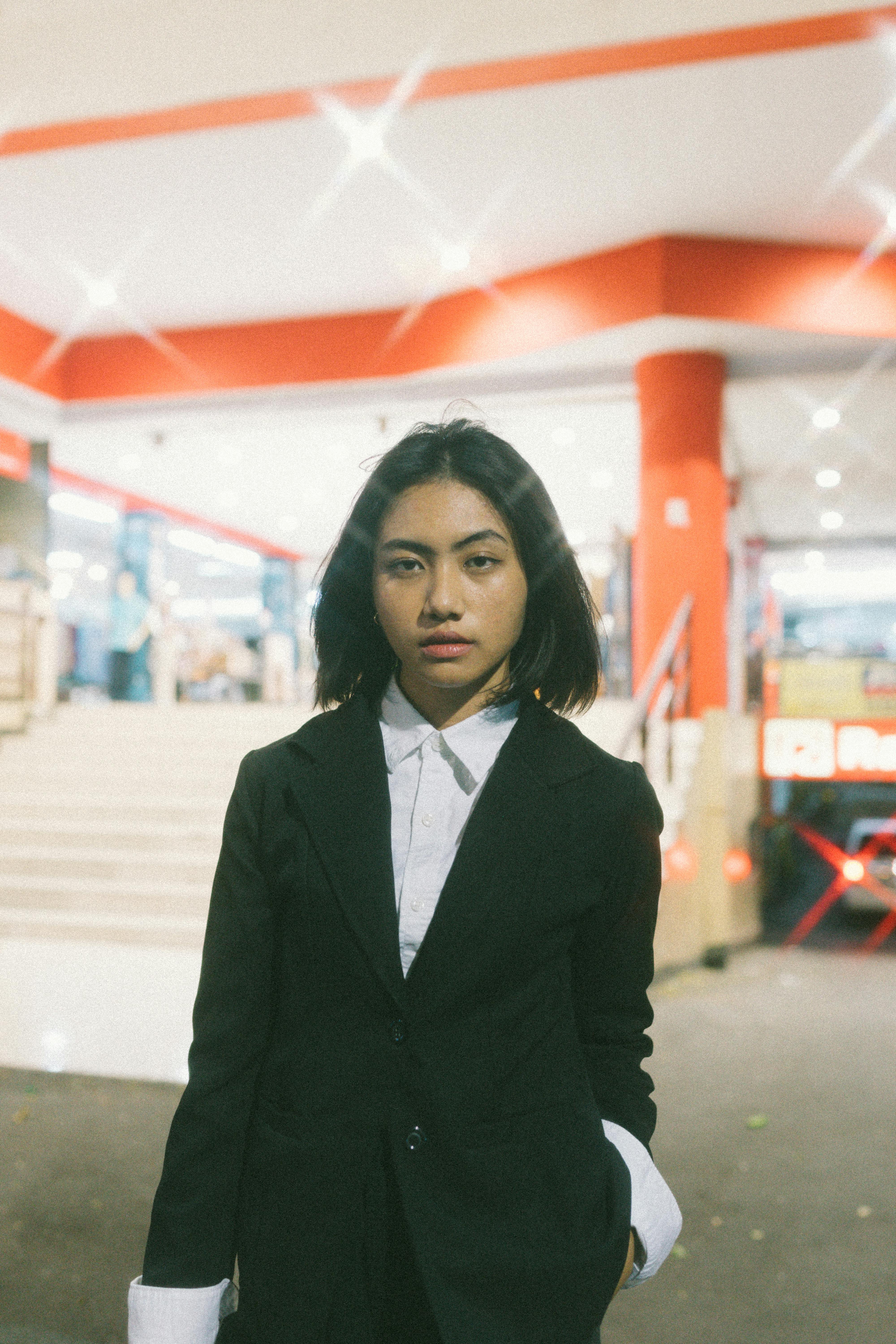 Portrait of a young woman in a suit posing outdoors at night. Stylish and modern look.