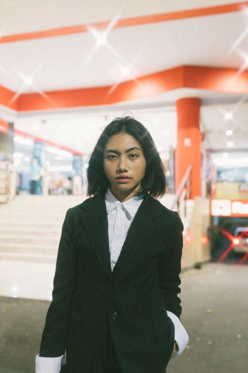 Free Portrait of a young woman in a suit posing outdoors at night. Stylish and modern look. Stock Photo