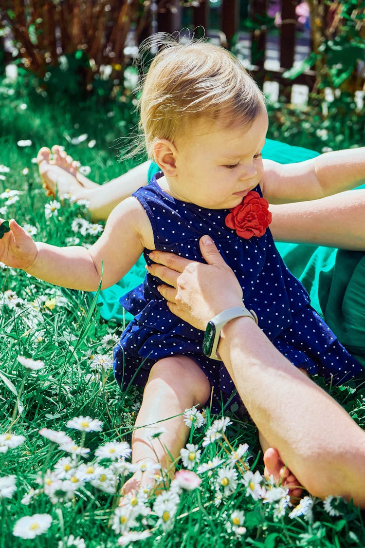 Baby Girl In Blue Dress Sitting On Grass