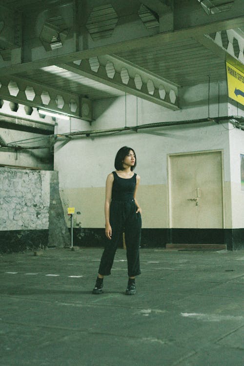 Woman in Blank Tank Top and Black Pants Standing on Gray Concrete Floor