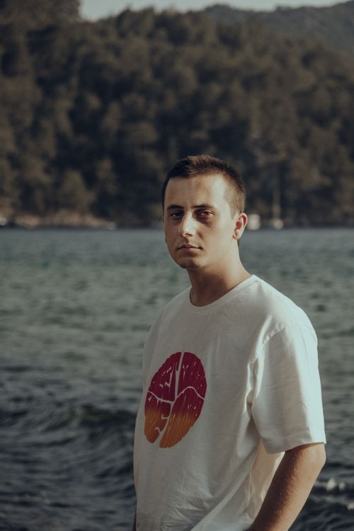 Free Portrait of a young man in a white shirt standing by the sea, conveying a calm and thoughtful vibe. Stock Photo