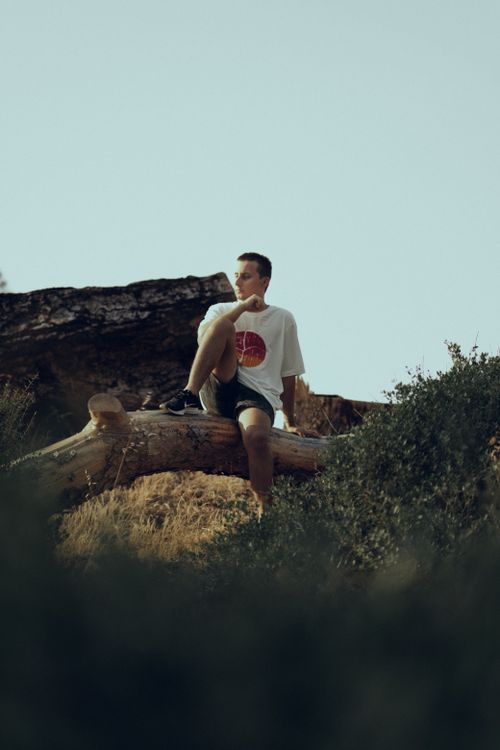 Free A man sits on a fallen tree in nature, enjoying a tranquil outdoor adventure moment. Stock Photo
