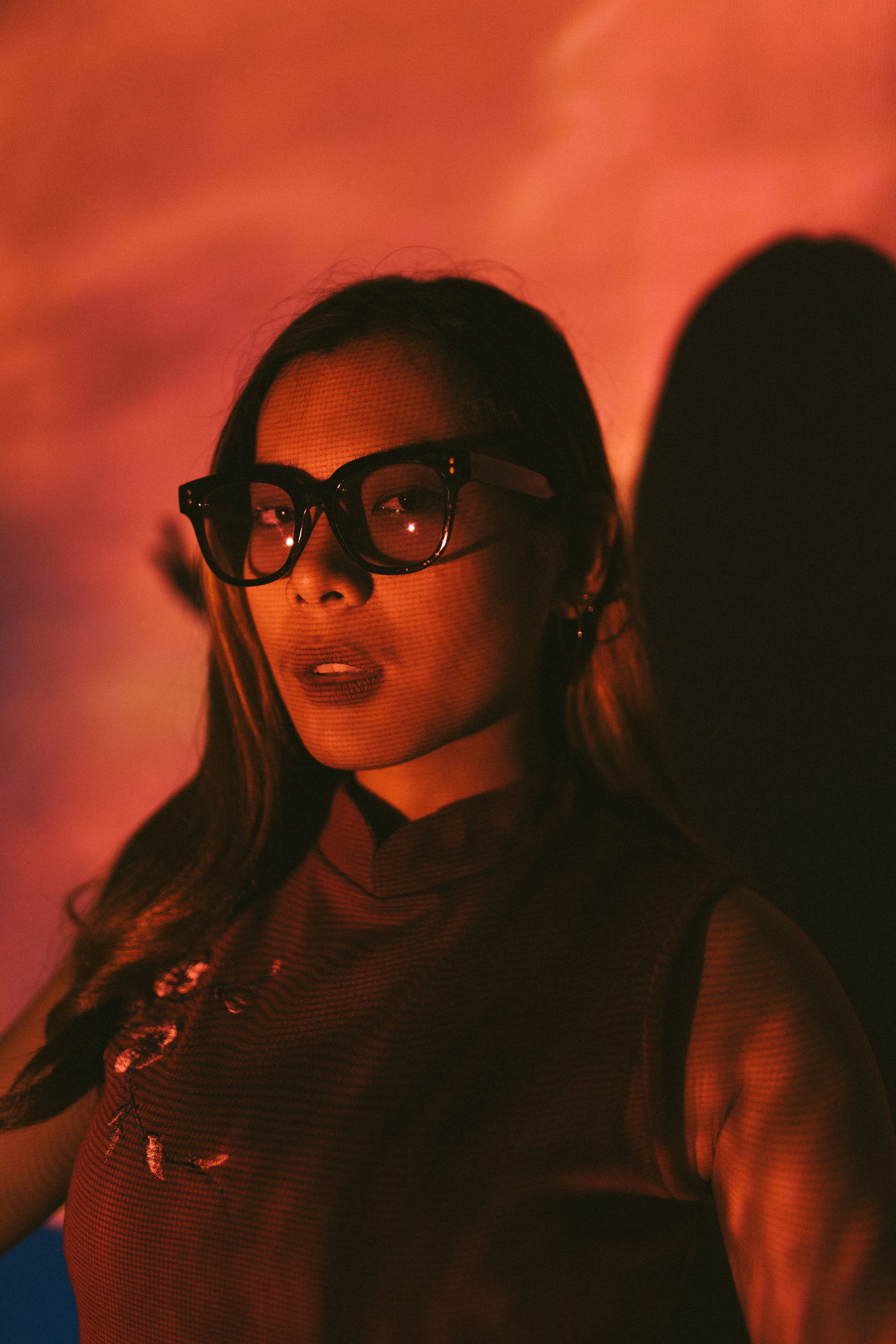 Moody portrait of a woman in sunglasses, enhanced by dramatic lighting and shadows.