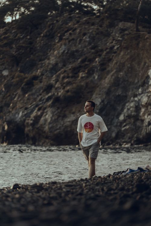 Free Adult man enjoying a peaceful walk along a rocky beach at dusk, surrounded by nature. Stock Photo