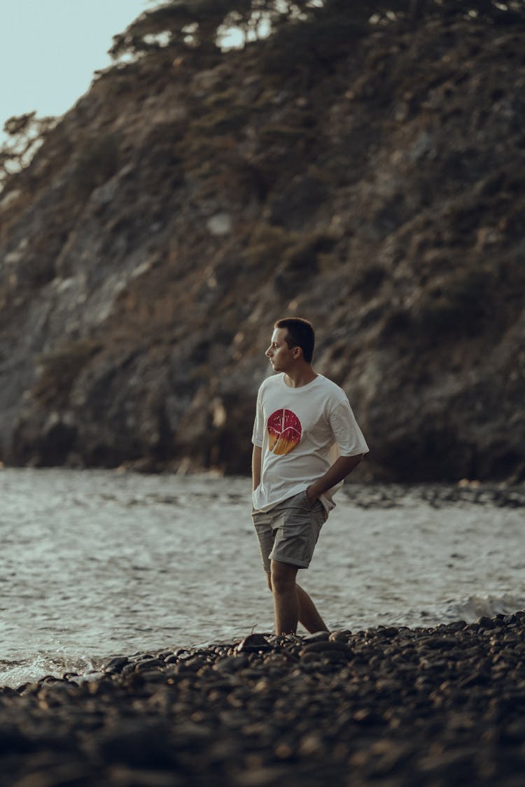 Man In White Shirt Walking On A Rocky Shore