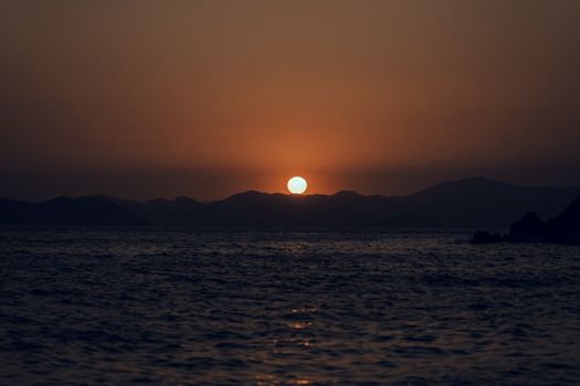 Captivating sunset over the ocean with mountains silhouetted against the vibrant sky.