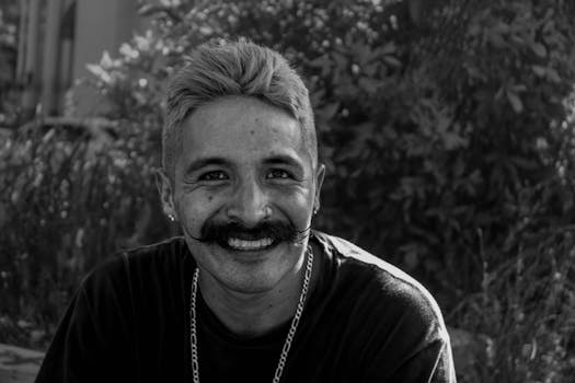 A monochrome portrait of a joyful man with a mustache outdoors in Monterrey, Mexico.