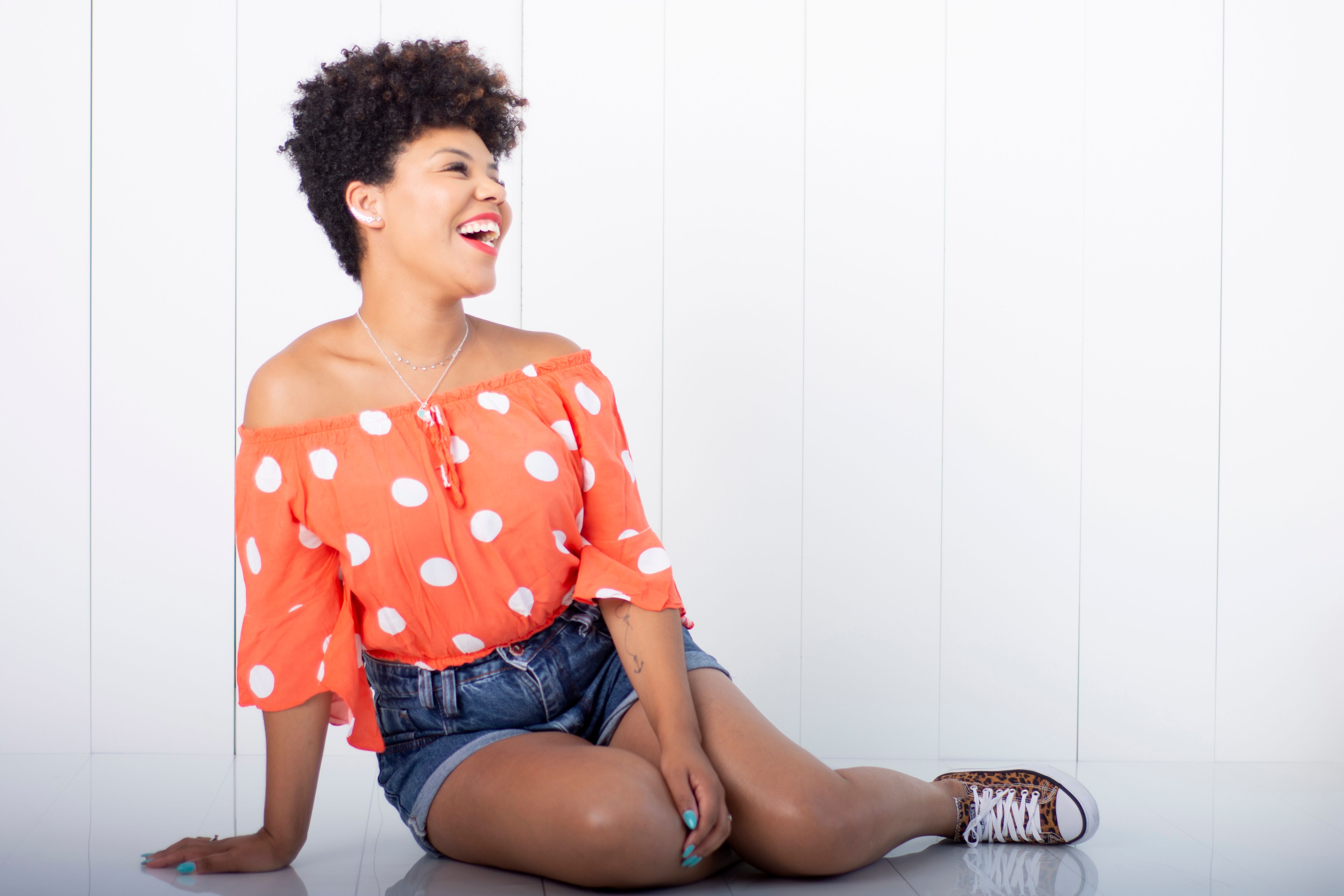 person sitting on the floor surrounded by clothes, laughing