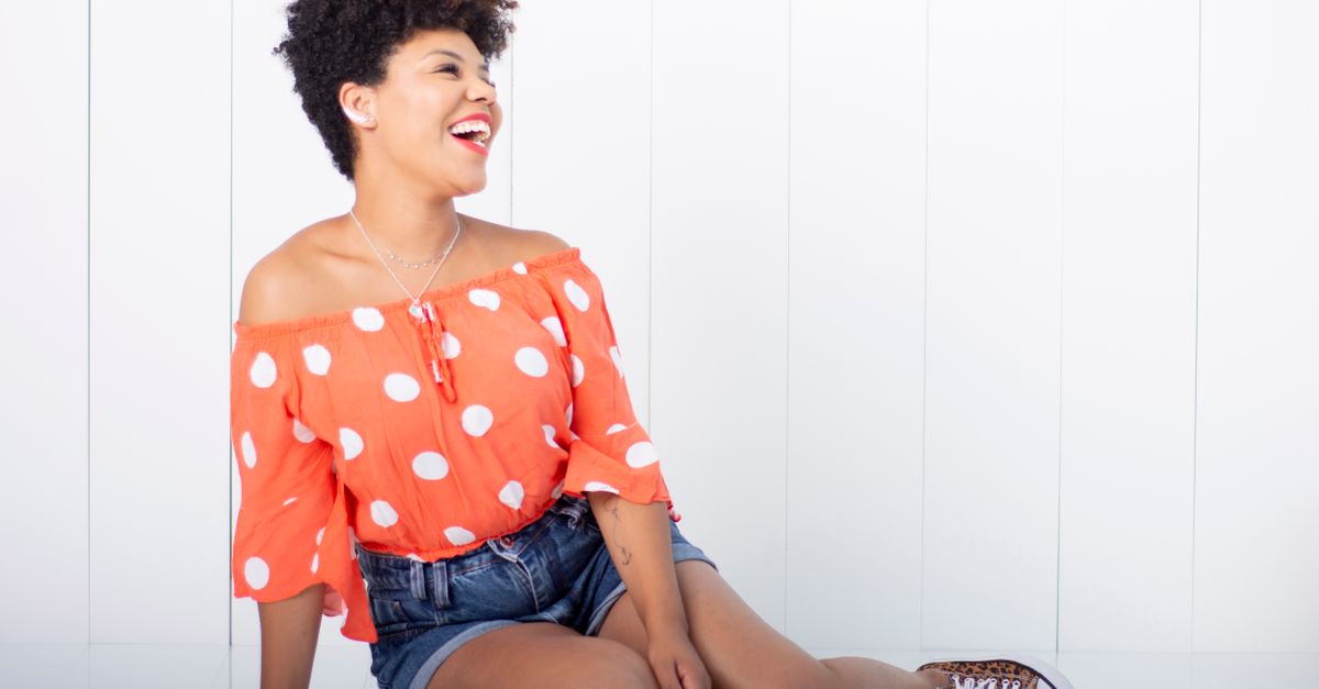 person sitting on the floor surrounded by clothes, laughing