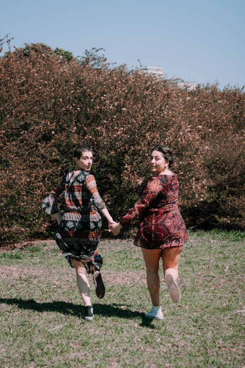 Women Holding Hands While Running in the Field