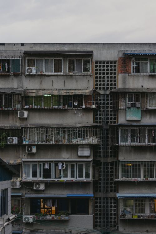 Free Concrete apartment exterior with metal grills and glass windows, showcasing urban living. Stock Photo