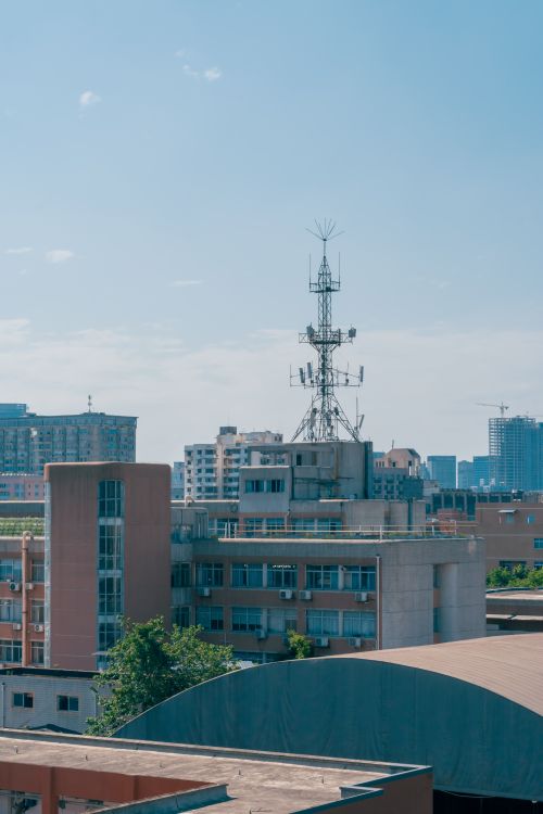Free A vibrant cityscape featuring a signal tower amidst modern buildings under a clear blue sky. Stock Photo