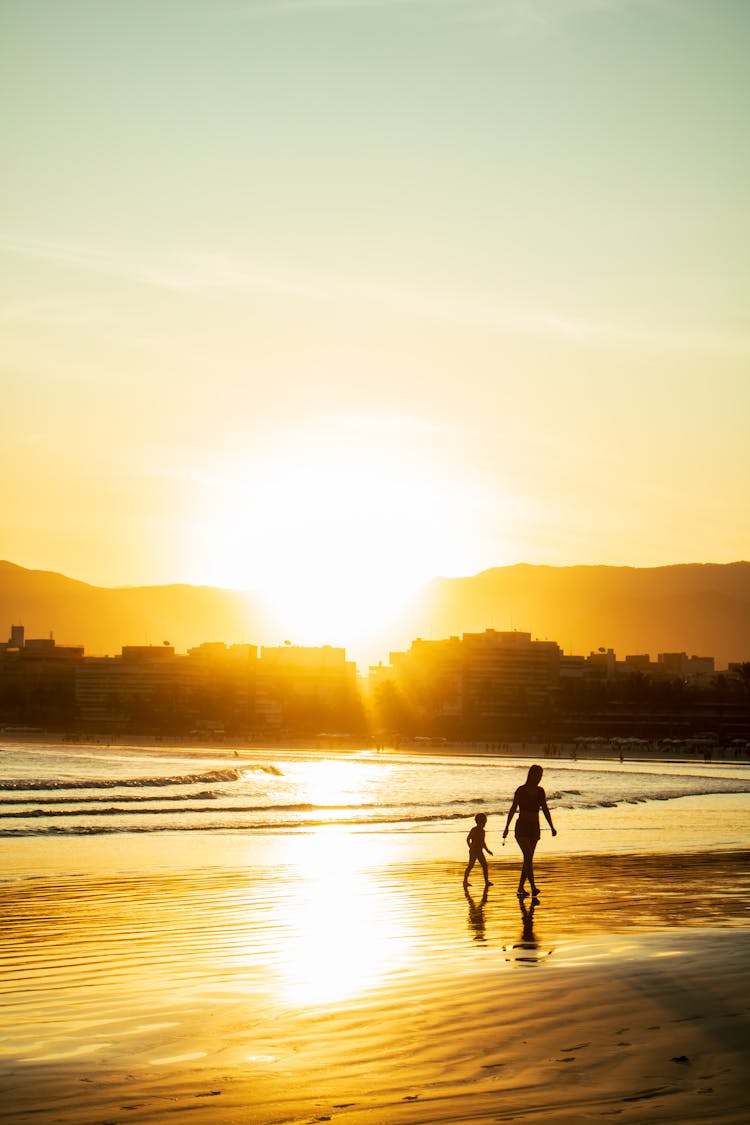 Mother And Child Walking On Sea Shore