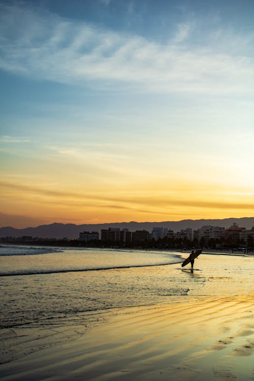 Free A  Silhouette of a Surfer Walking on the Seashore Stock Photo