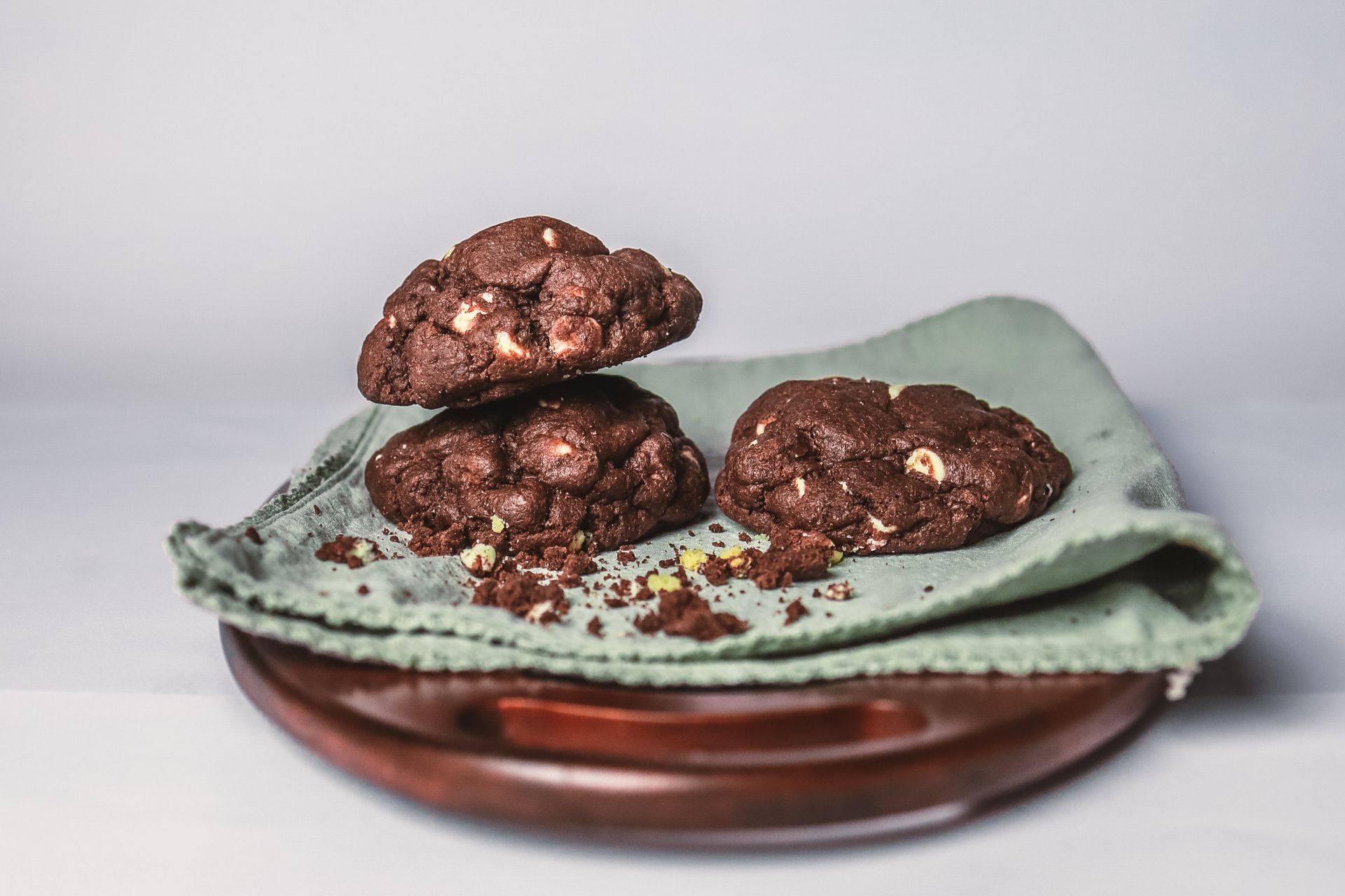 Close-up of chocolate cookies with chips on a wooden tray with cloth.
