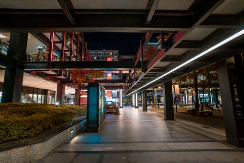 Free Modern outdoor shopping area with steel structures and ambient lighting at night. Stock Photo