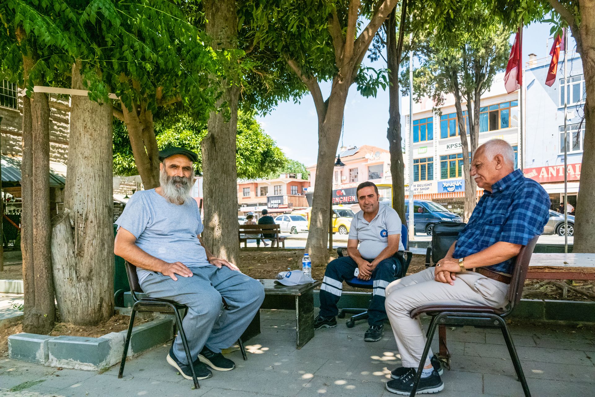 A group of elderly men sitting and chatting in an outdoor park area.