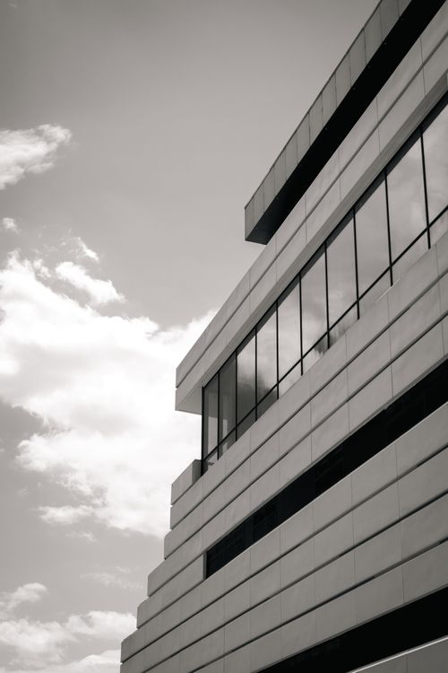 Free Black-and-white photo of a modern building exterior against cloudy sky. Stock Photo