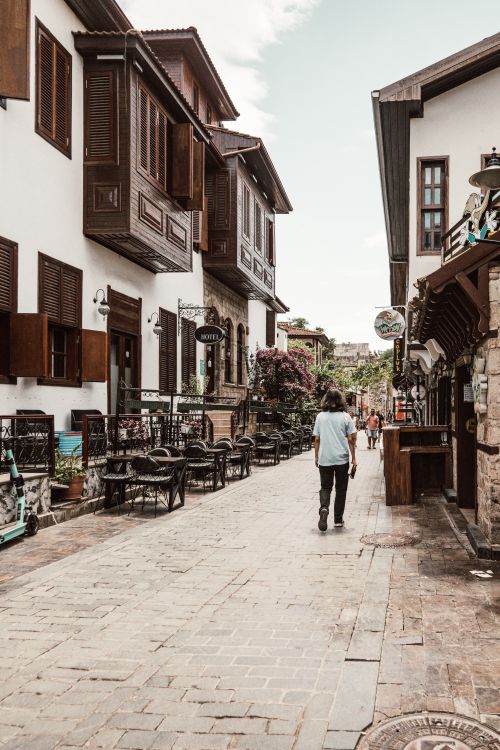 Free A picturesque narrow street with wooden buildings and outdoor cafes, featuring a person walking. Stock Photo