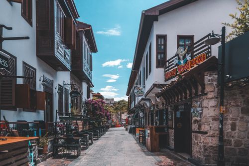 Free Explore a charming urban alleyway lined with quaint facades and vibrant outdoor seating, perfect for a stroll. Stock Photo
