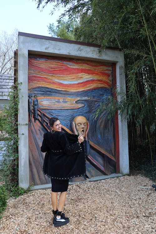 Woman in Black Coat Standing Beside a Wall Painting