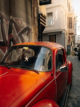 Classic orange Volkswagen Beetle parked in a narrow alley in Istanbul, Turkey, with charming urban surroundings.