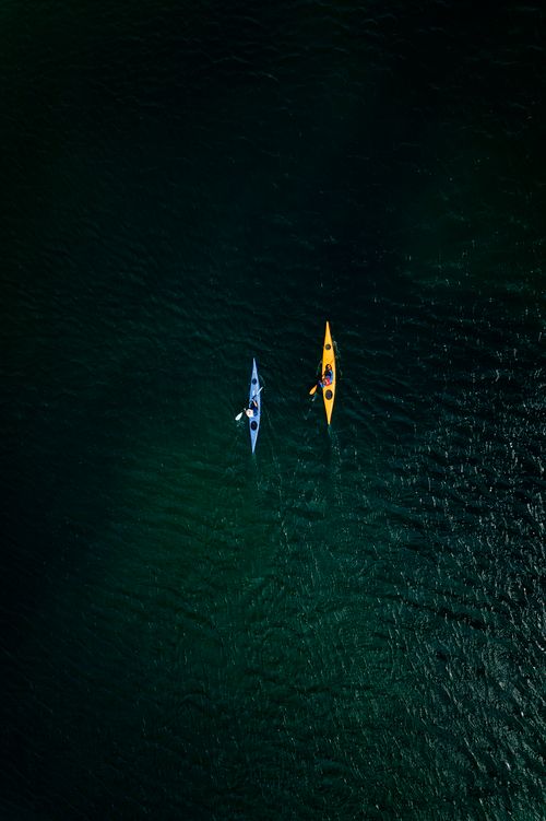 Free Overhead shot of two kayaks in the serene waters of the English coast, showcasing vibrant colors and textures. Stock Photo