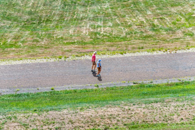 Aerial Photography Of Two People Walking Concrete Road Together