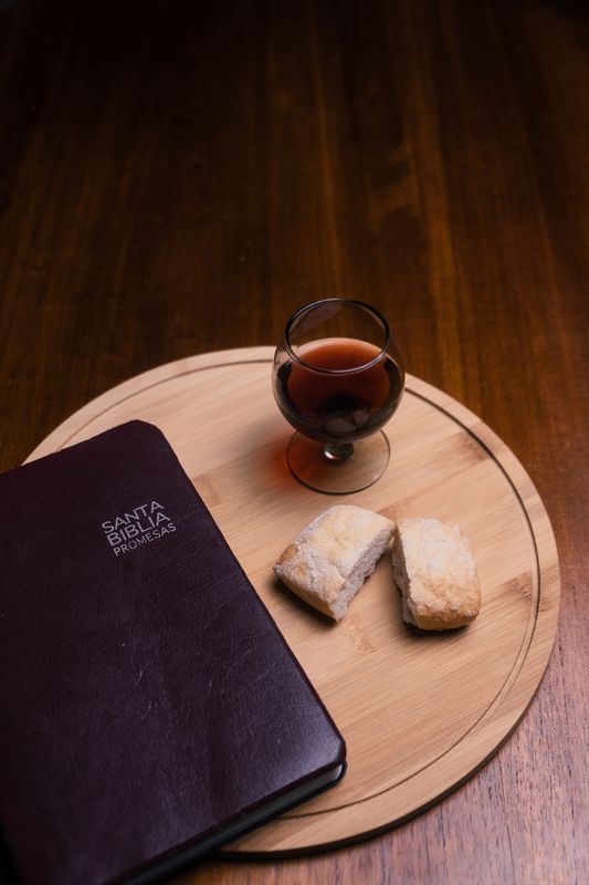 A Bible, bread and cup on a wooden table - The TWO Church Ordinances