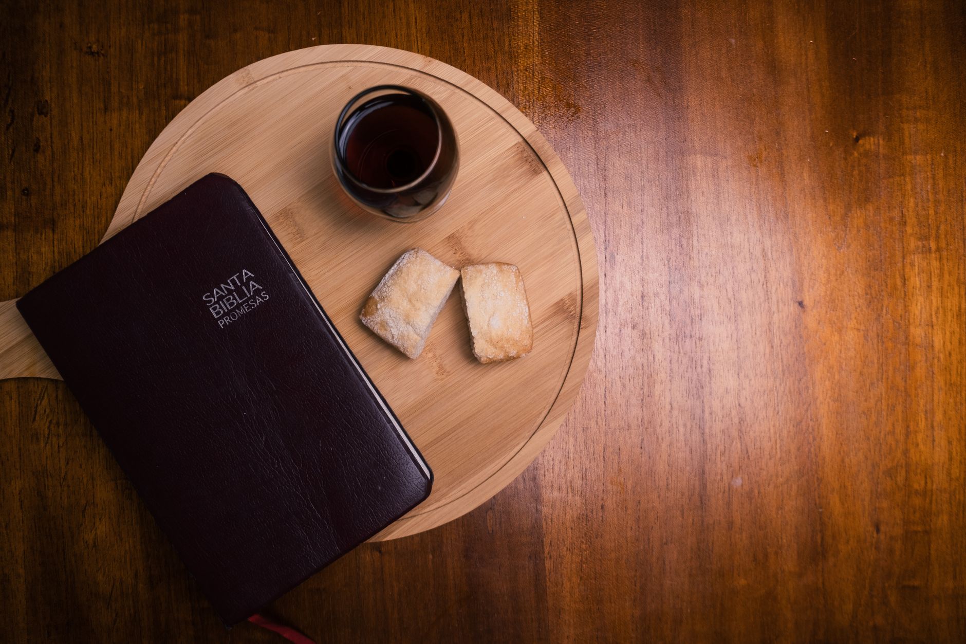 Flat lay image of a Bible, coffee, and bread on a wooden surface, creating a rustic and peaceful scene.
