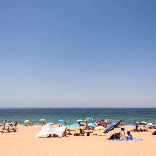 Free Lively summer beach scene with colorful umbrellas and people enjoying the sunny day. Stock Photo