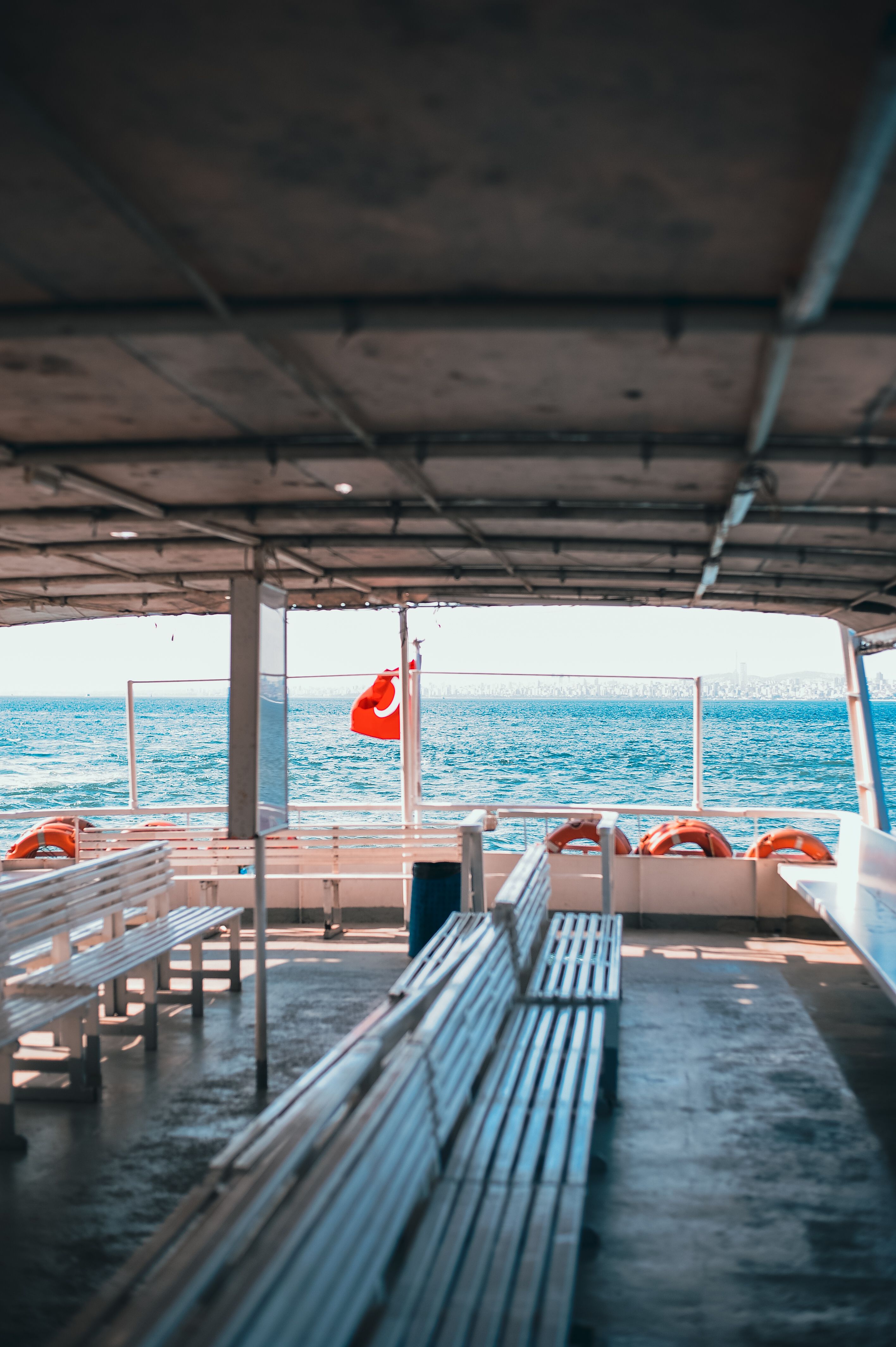 Sunlit ferry boat interior with benches, open sea, and scenic view creating a calm ambiance.