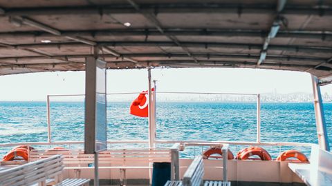 Sunlit ferry boat interior with benches, open sea, and scenic view creating a calm ambiance.