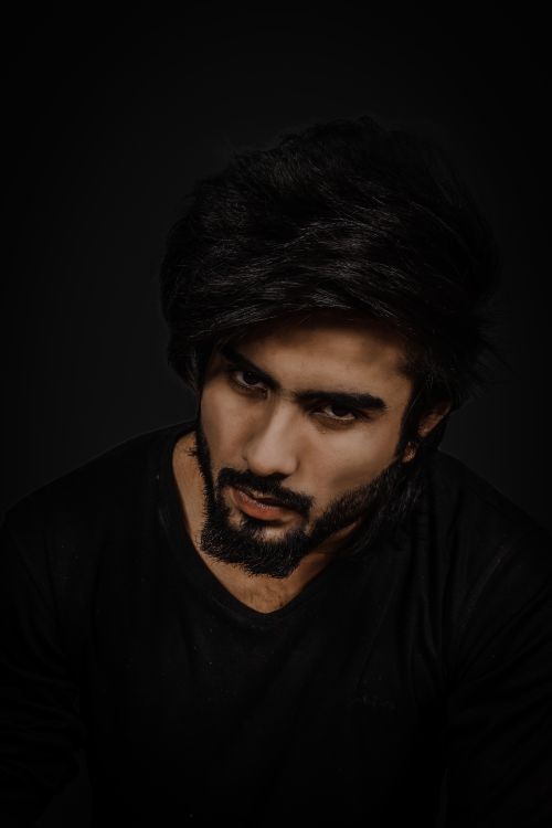 Free Close-up portrait of a bearded man in a black shirt against a dark background, exuding a moody vibe. Stock Photo