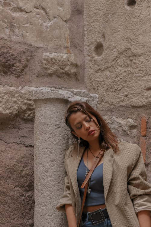 Woman in Beige Blazer Leaning on Concrete Wall